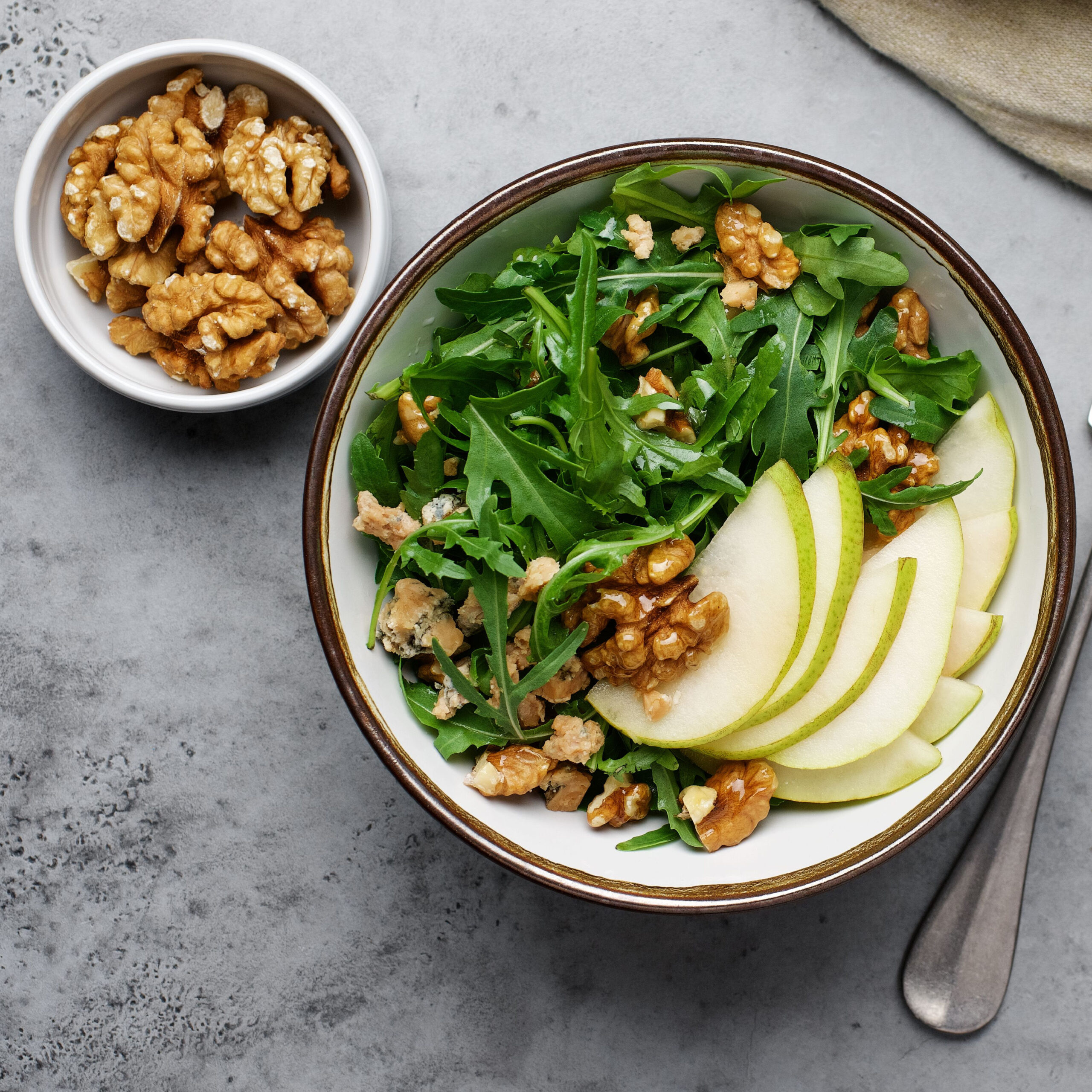 arugula salad topped with apples and nuts