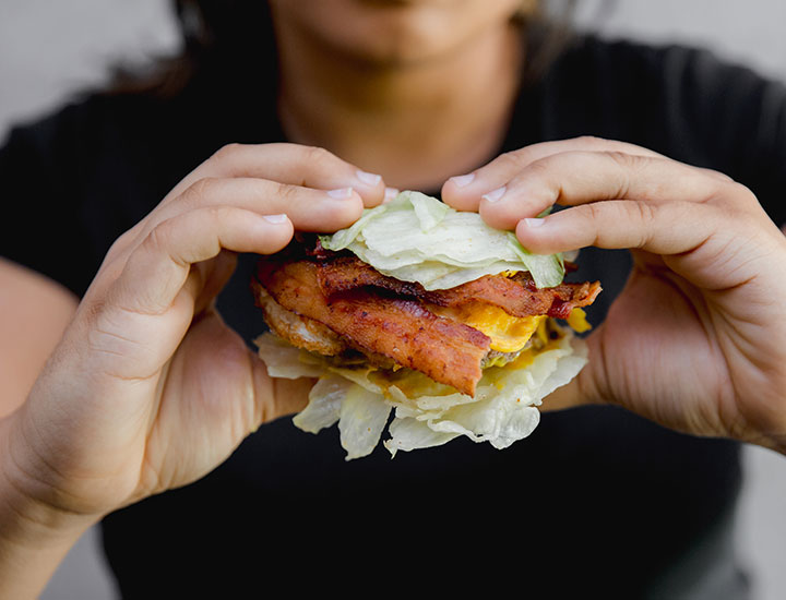 Woman eating a keto burger without a bun with carbs