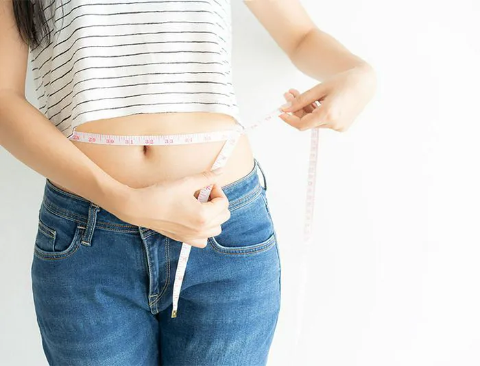 Woman measures waist.