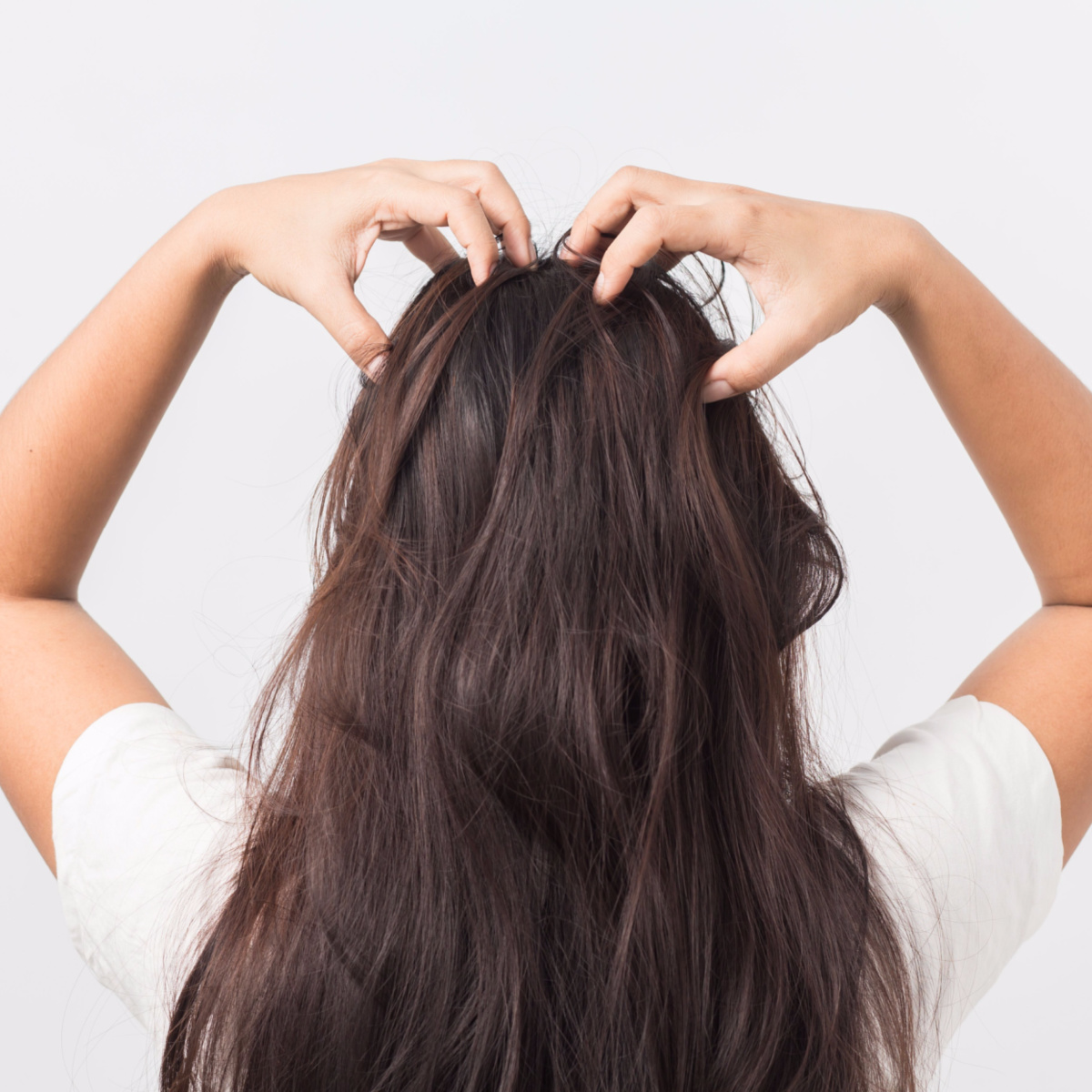 woman scratching itchy scalp massaging roots of long brown wavy hair behind back of head