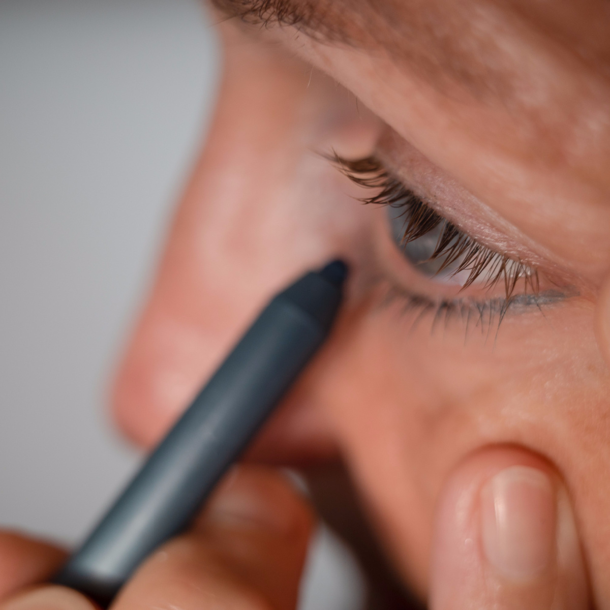 woman applying eyeliner to bottom waterline lashine