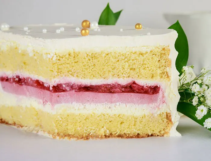 Close up of slice of yellow cake with white icing and strawberry filling
