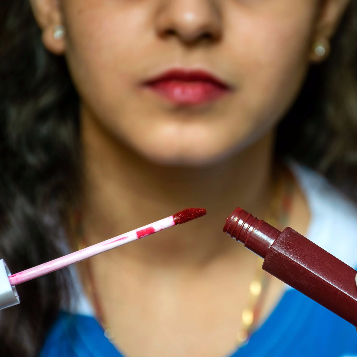 woman applying dark lipstick liquid matte product to lips wand