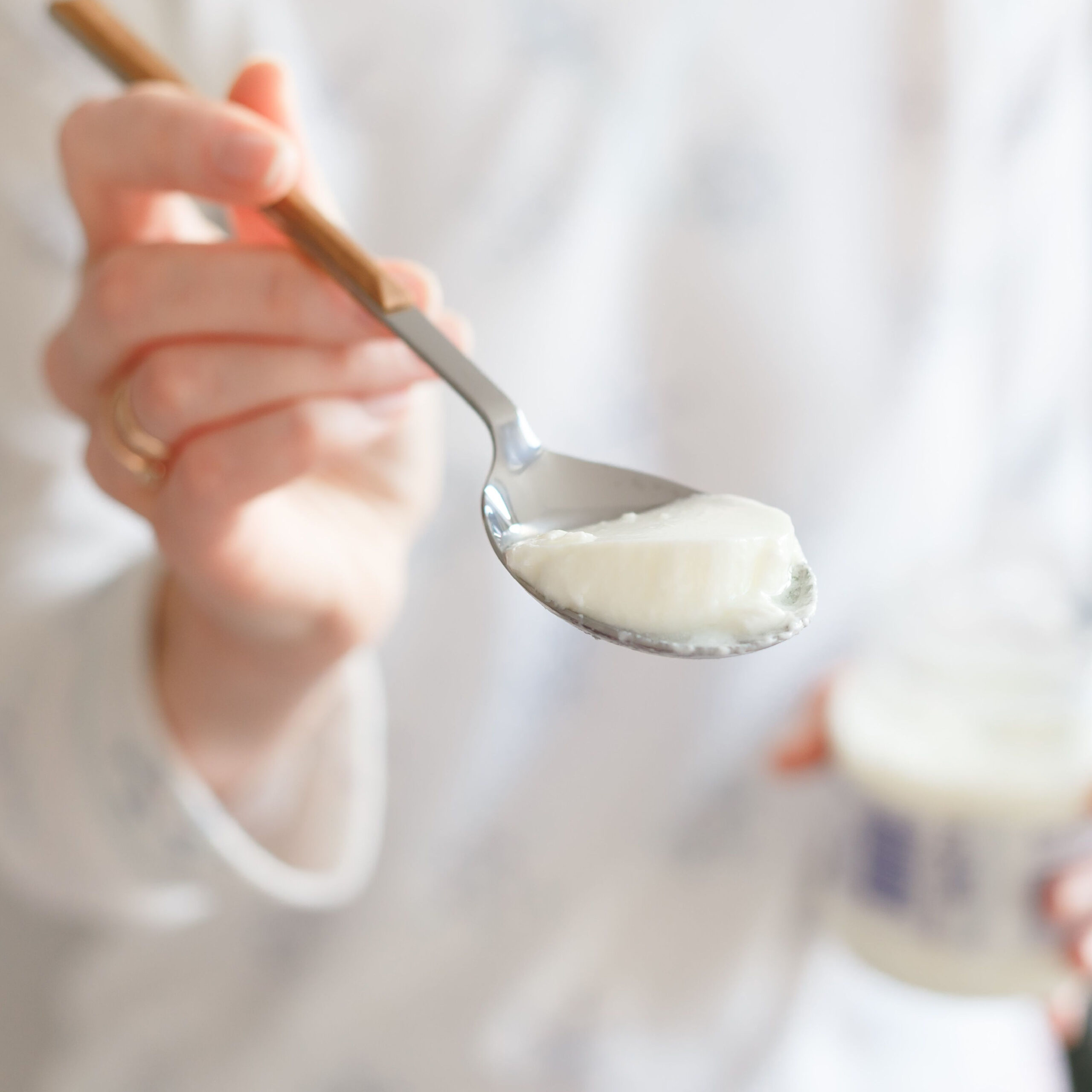 woman holding spoonful of greek yogurt