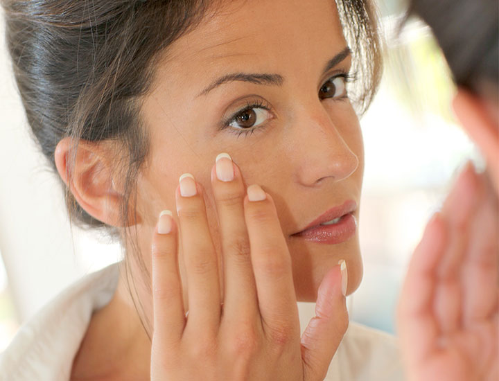 woman-applying-makeup-in-mirror