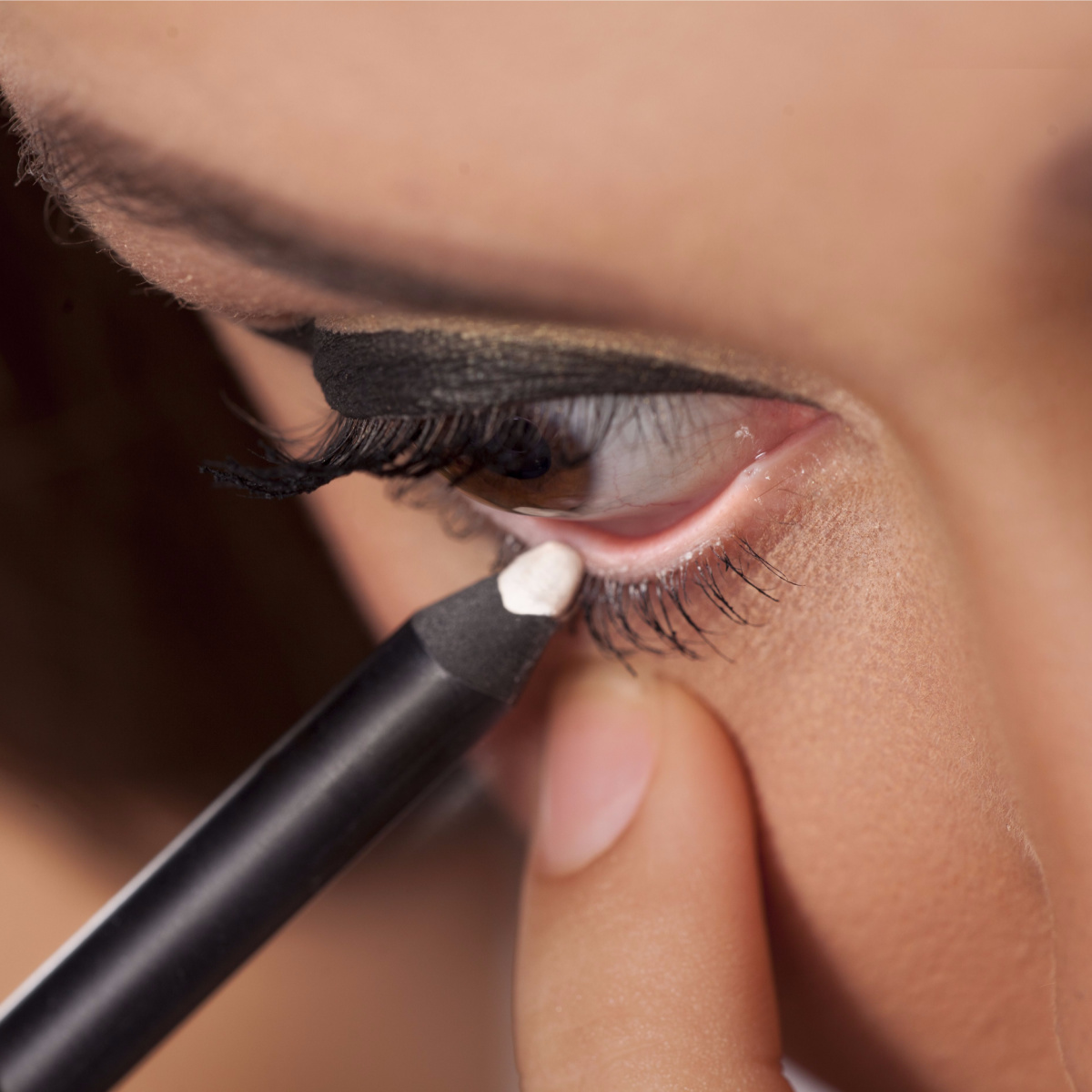 woman applying white eyeliner to bottom lash line waterline