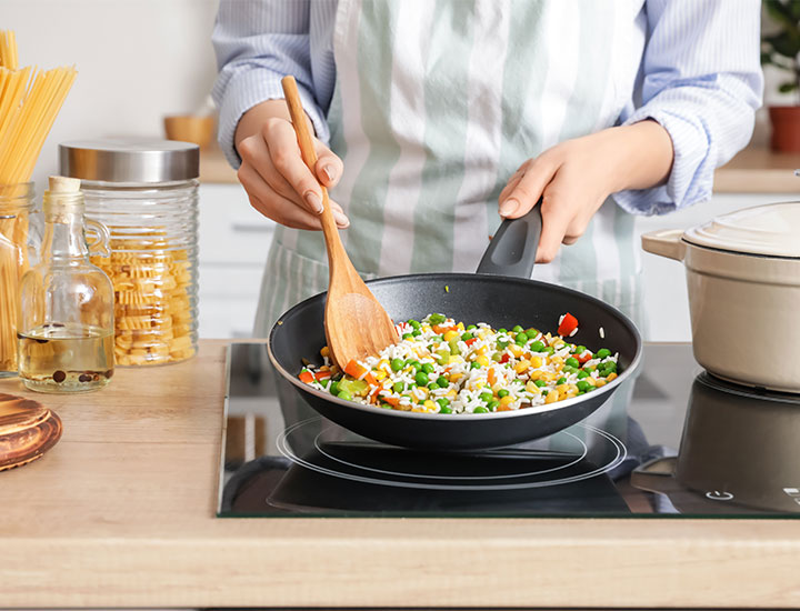 Woman cooking rice and veggies at home