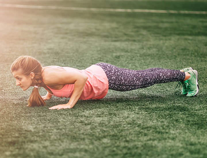Woman doing burpees on grass