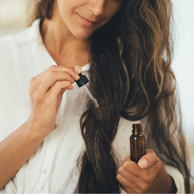 woman putting serum oil in hair ends of locks