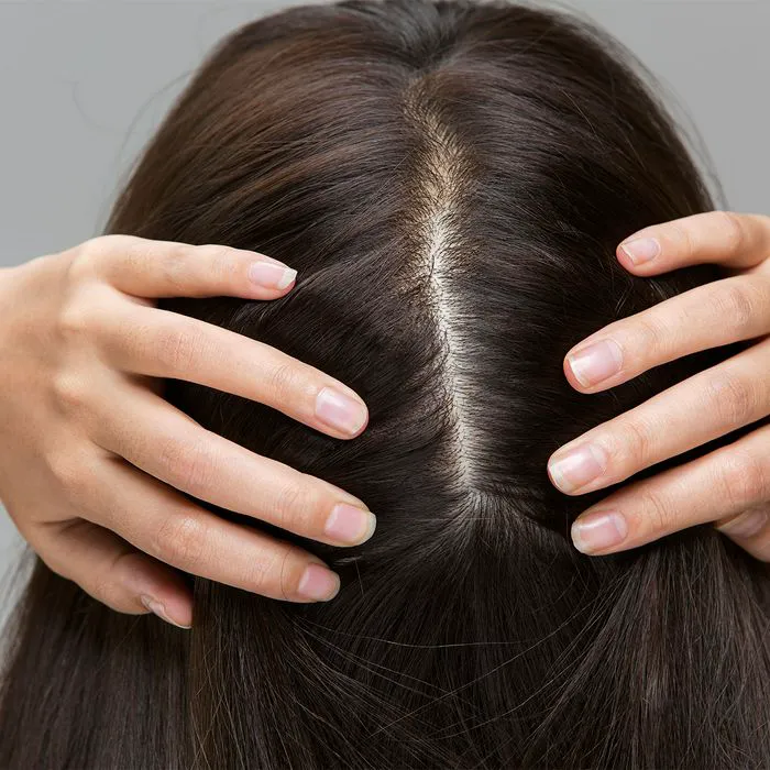 woman parting her hair to reveal scalp long dark hair