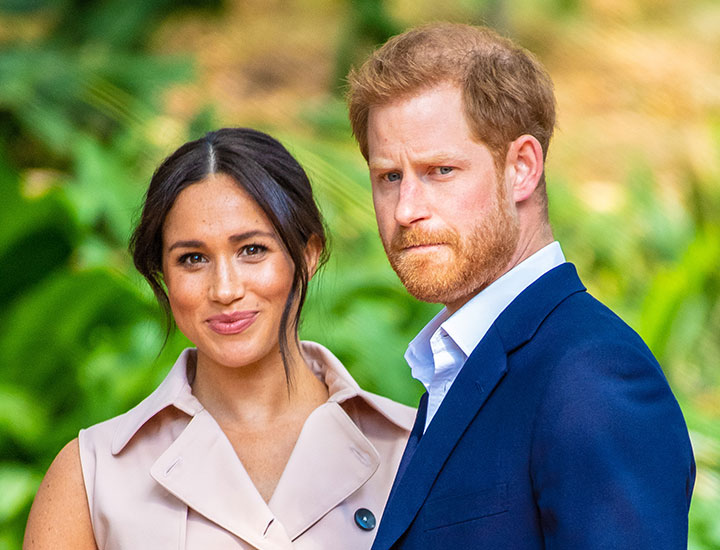 Prince Harry frowning Meghan Markle smirking