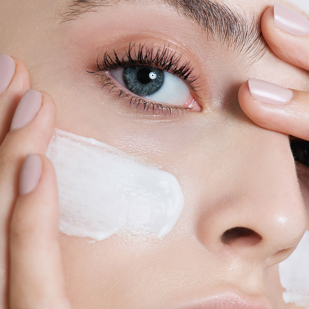 woman applying white sunscreen under-eye middle of face