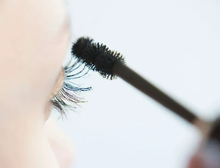 side profile applying mascara wand lashes