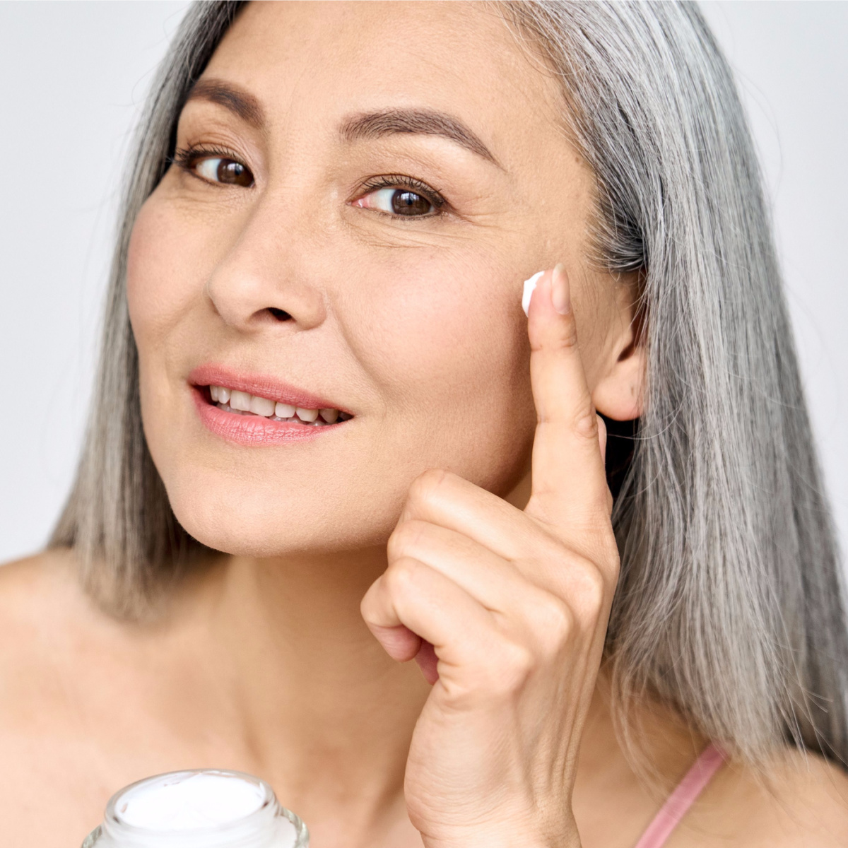 mature senior gray hair woman applying white sunscreen