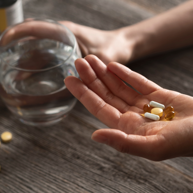 handful of supplements with glass of water