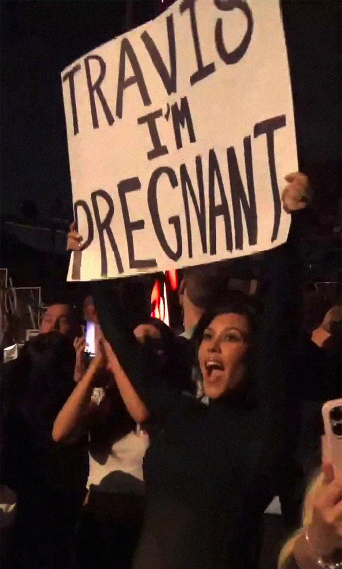 Kourtney Kardashian holding up a sign that says 