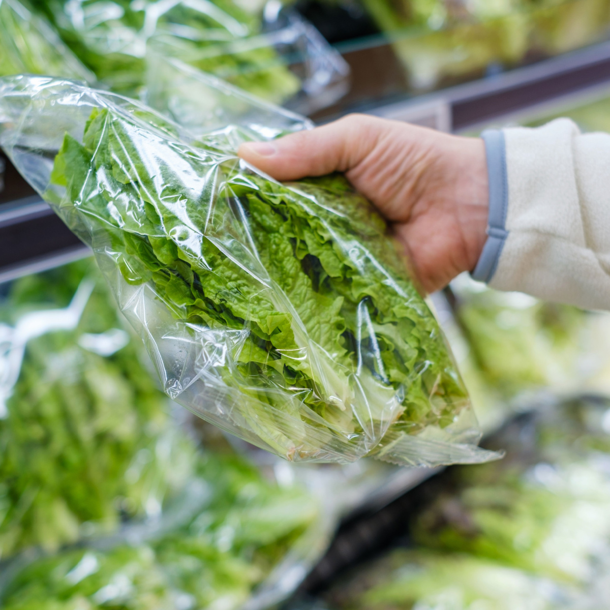 hand holding bag plastic lettuce supermarket grocery store aisle