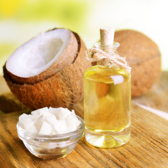small bottle of coconut oil beside coconuts
