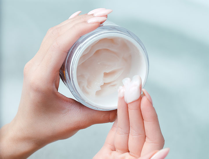 hands scooping out skincare cosmetic cream