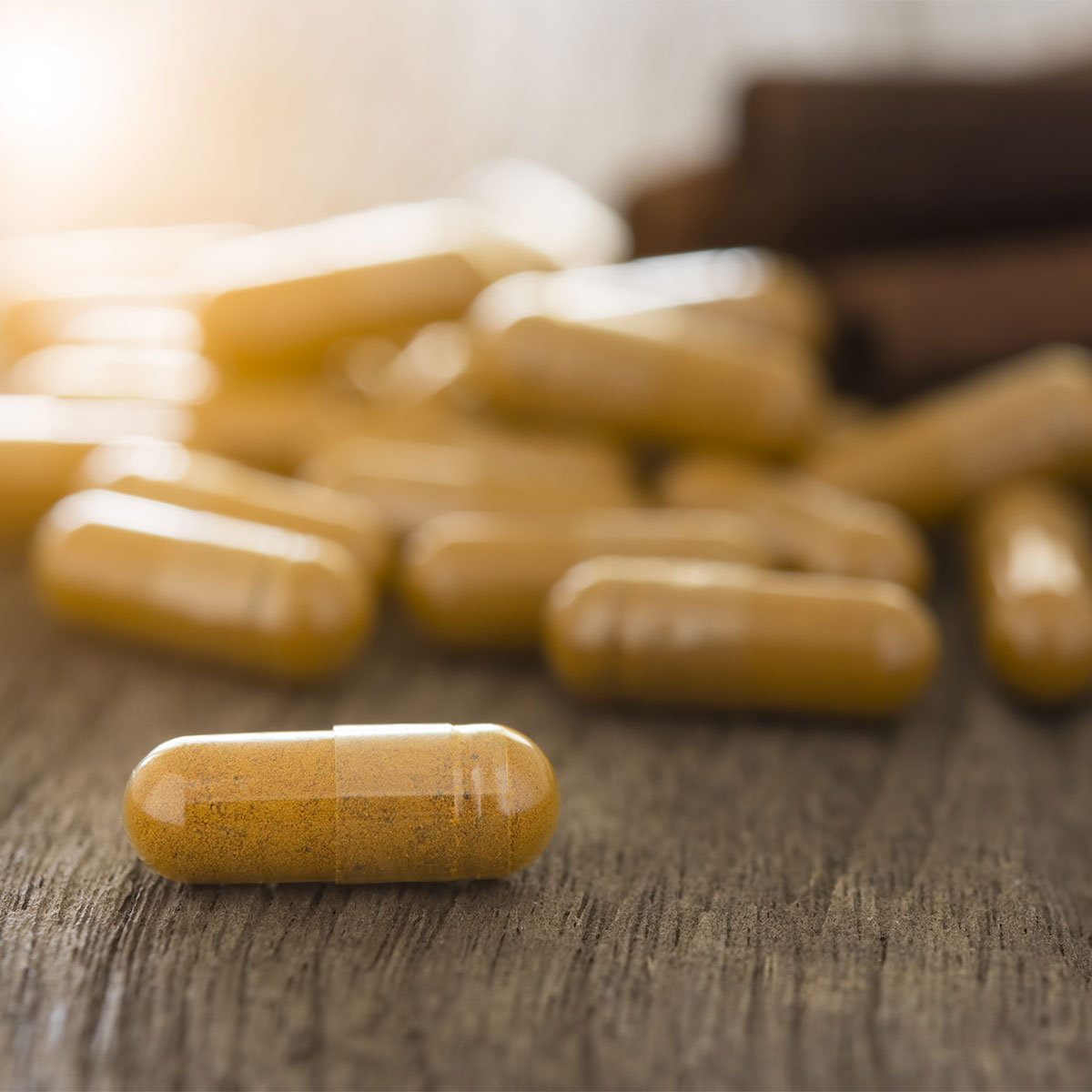 herbal supplements spilling out of bottle onto wooden table