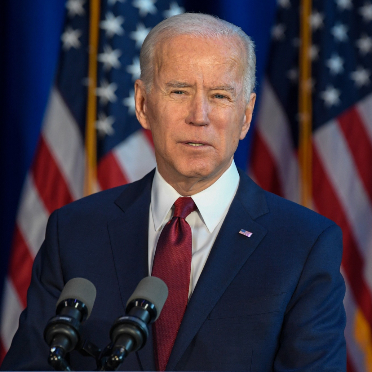 joe biden giving speech podium american flags