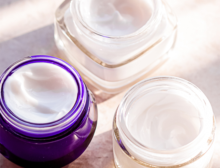 three skincare jars with creams clear and purple