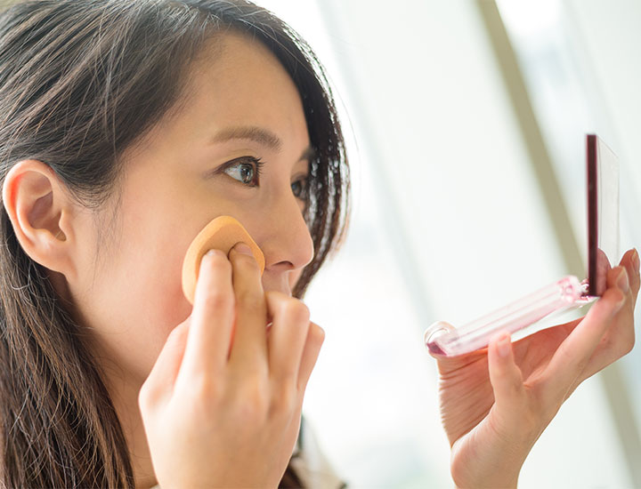 woman-applying-makeup-sponge