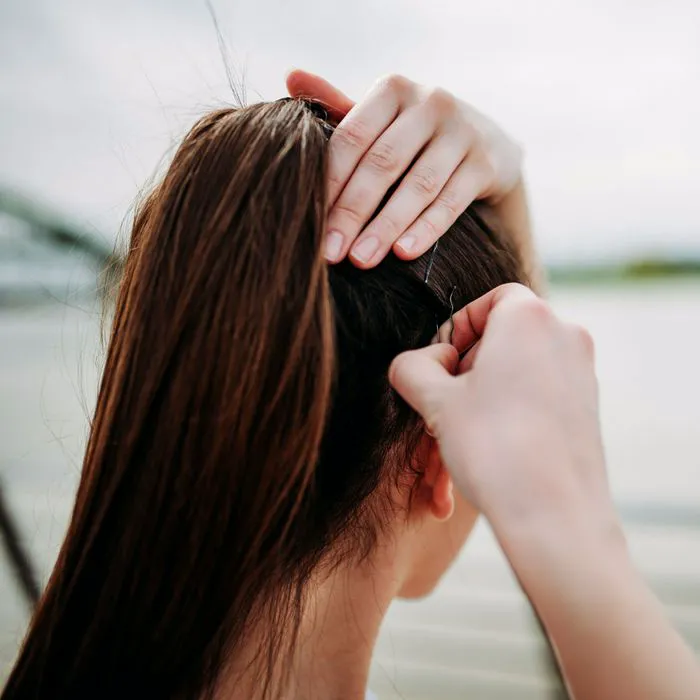 woman pinning hair back with bobby pins tight ponytail