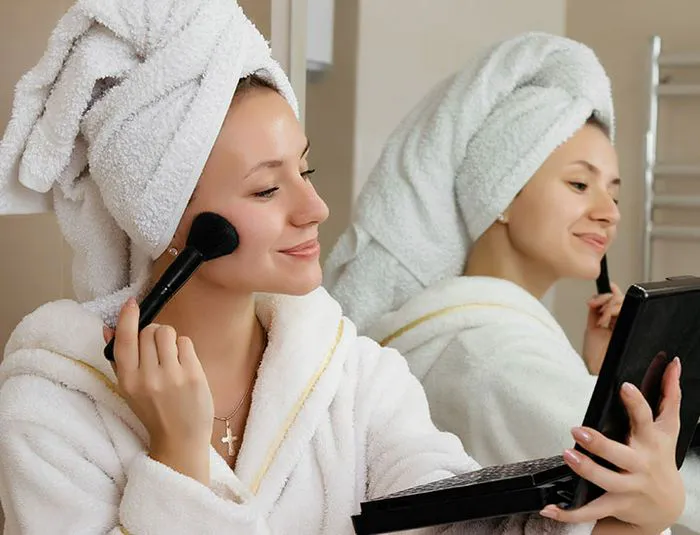 woman-applies-makeup-bathrobe
