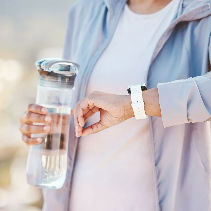 "Woman doing cardio workout with water and fitness watch"