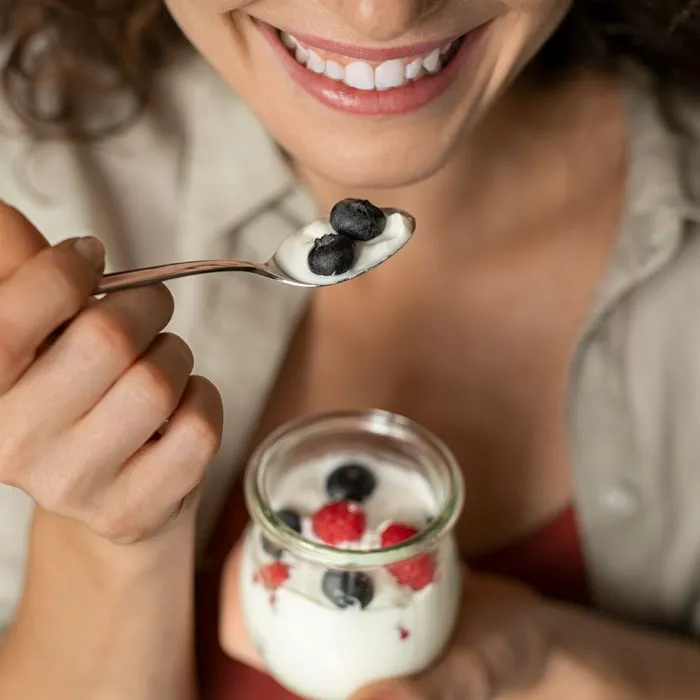 woman eating yogurt with blueberries
