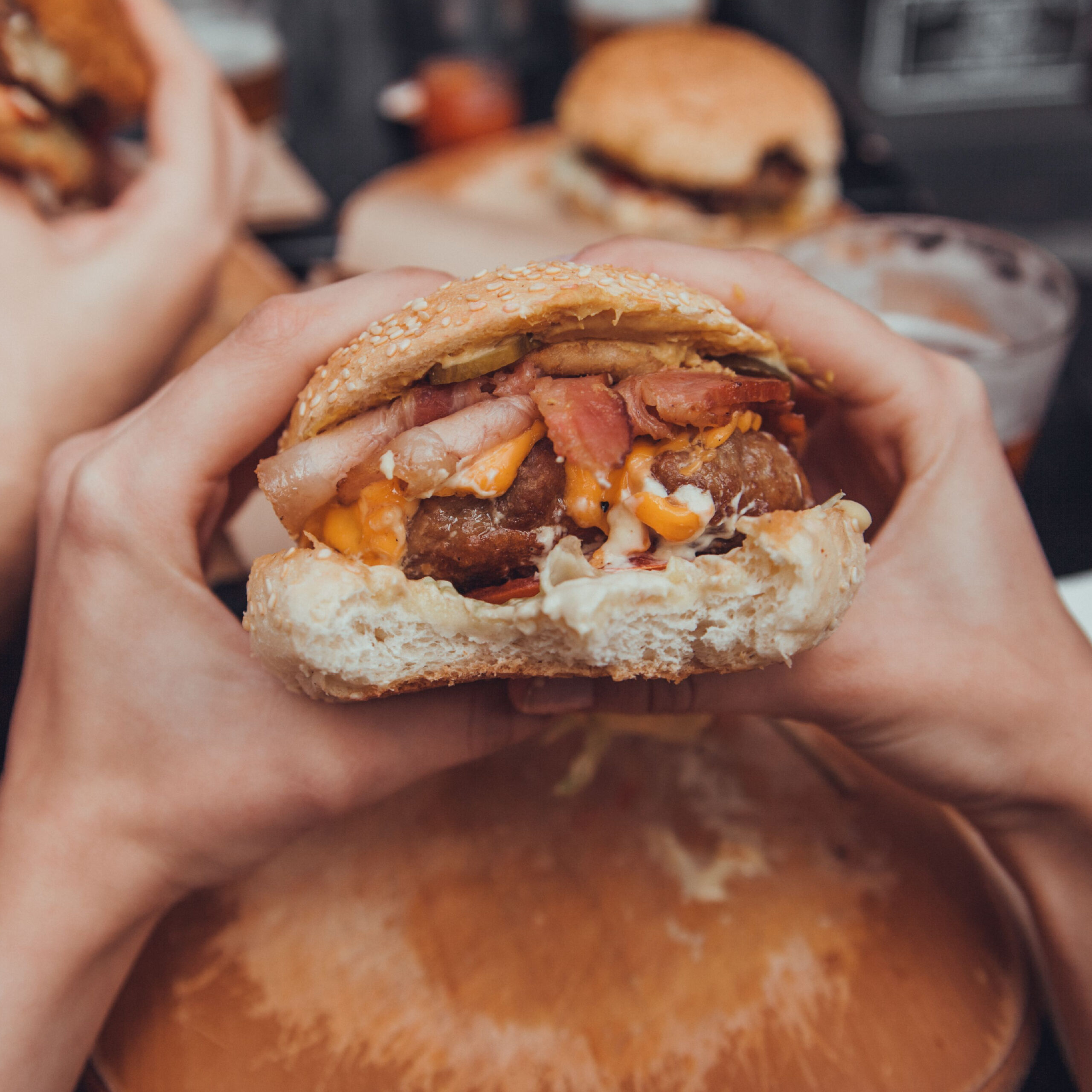 hands holding bacon cheeseburger