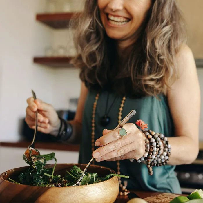 Happy middle-aged woman preparing a fresh salad for healthy eating.