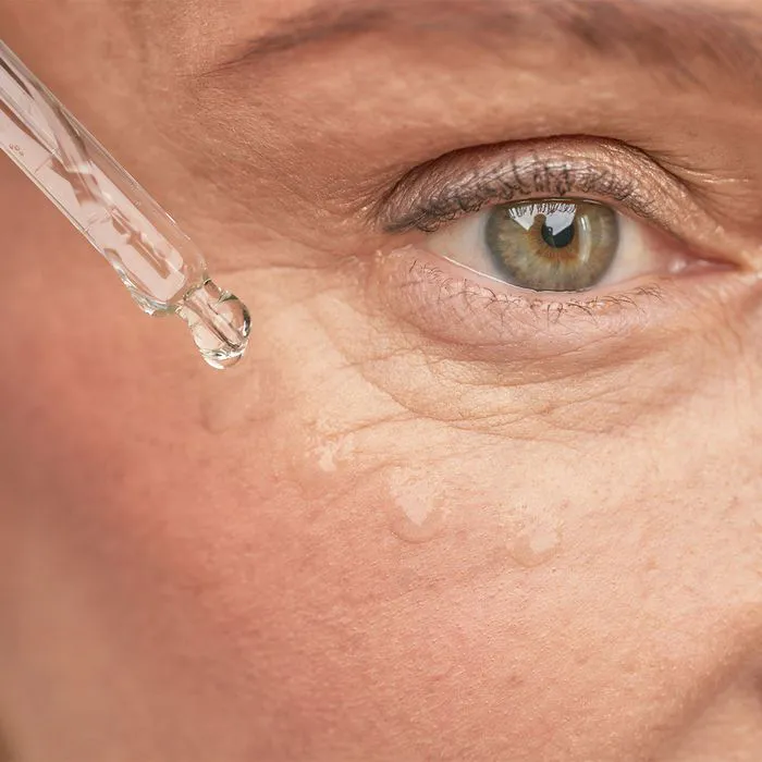"Woman applying skincare serum to her eye wrinkles"