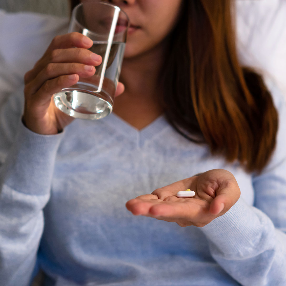 woman taking sleeping pill in bed