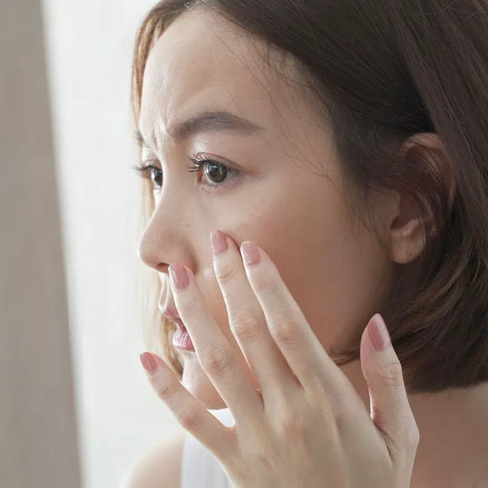 "Young woman concerned with under-eye wrinkles"