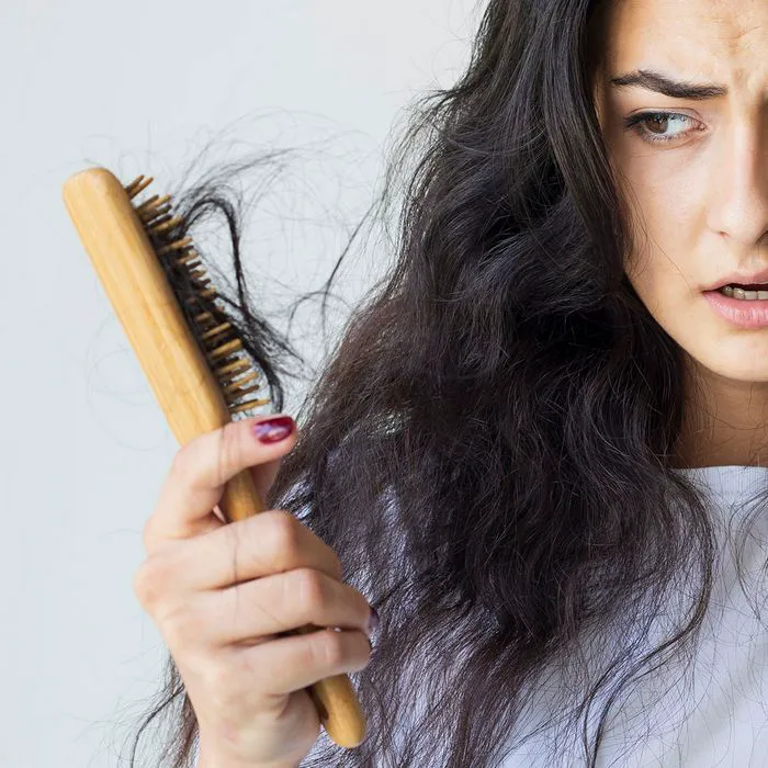 Young woman dealing with hair loss, expressing concern.