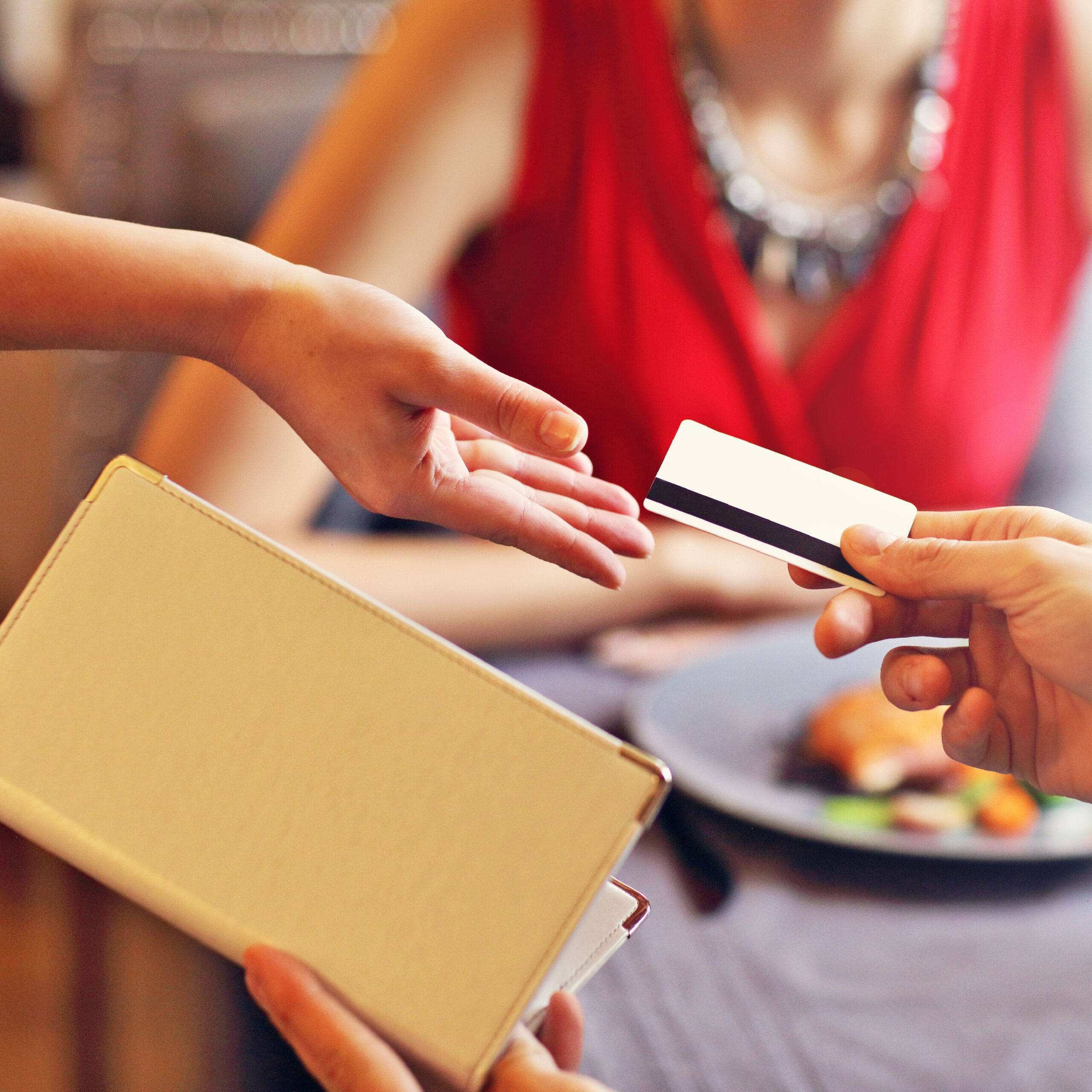 person handing credit card to pay bill at restaurant