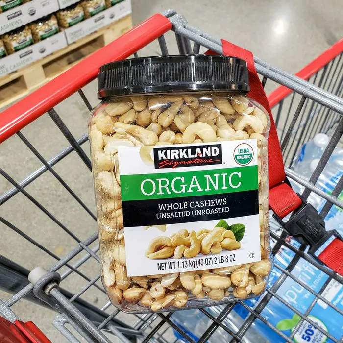 Jar of Kirkland cashews in a shopping cart at Costco.