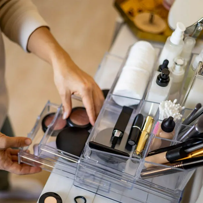 Woman selecting makeup products from a vanity storage organizer.