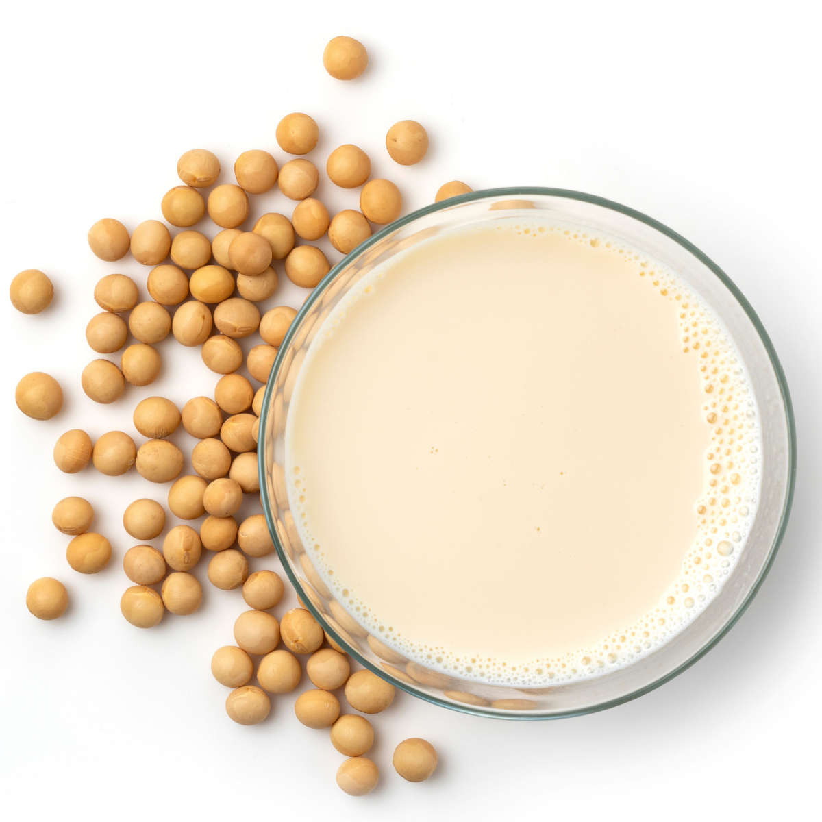 above view of glass of soy milk surrounded by soy beans