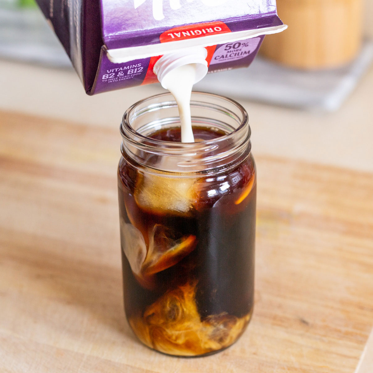 soy milk pouring into glass of coffee