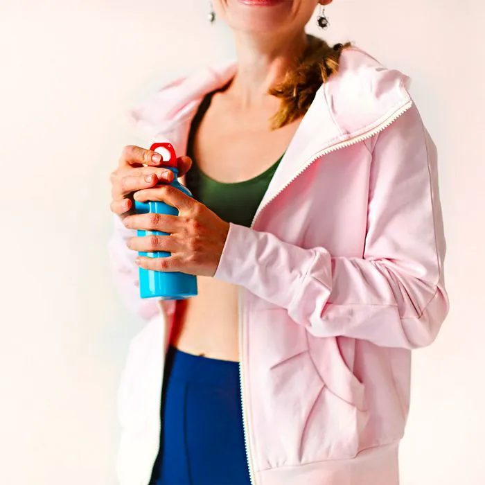 Woman in colorful workout attire holding a water bottle.
