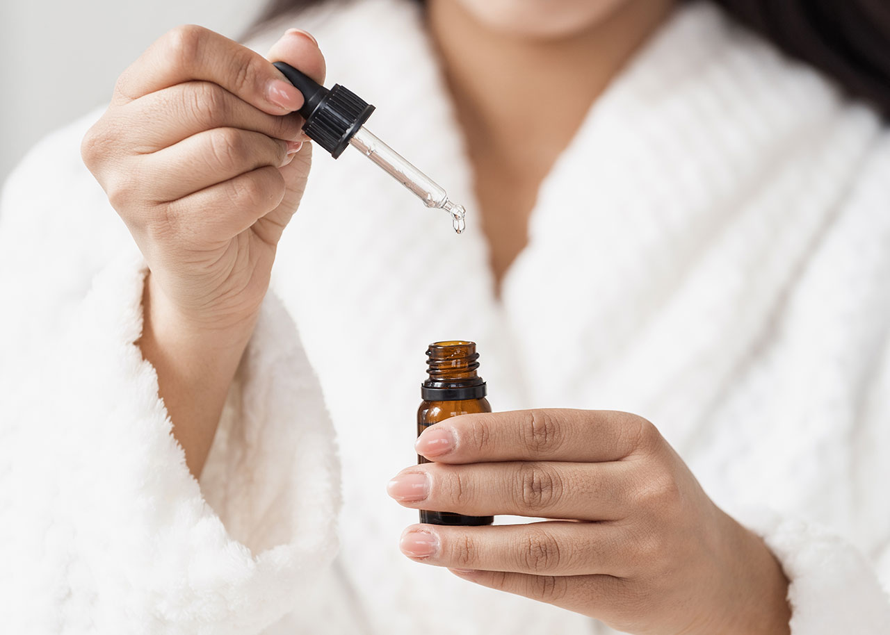 woman-wearing-robe-applying-serum