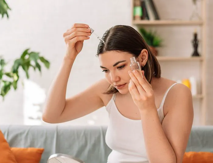 Lady examining reflection while applying scalp oil.