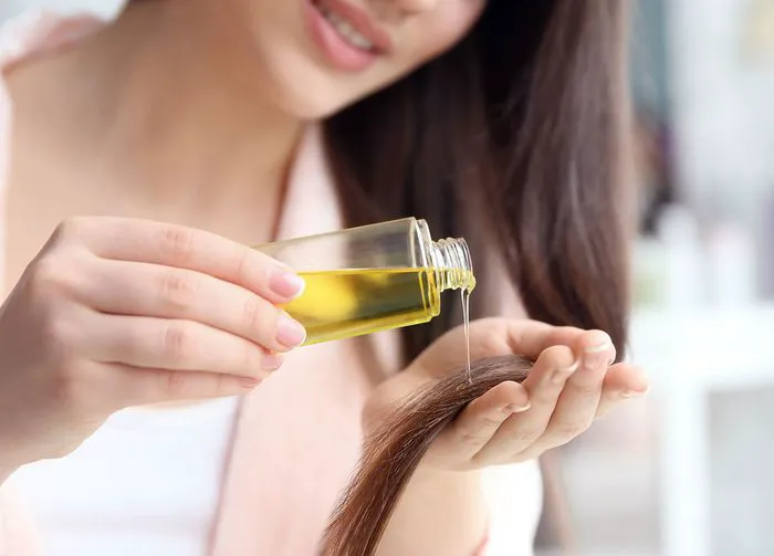 Woman treating split ends with hair oil application.