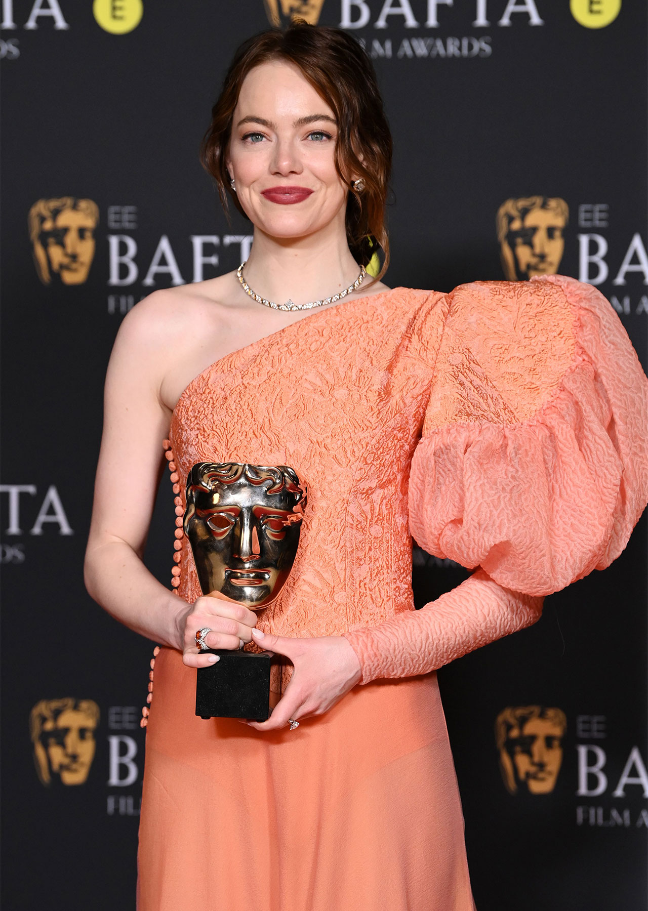 emma stone holding statue baftas film awards