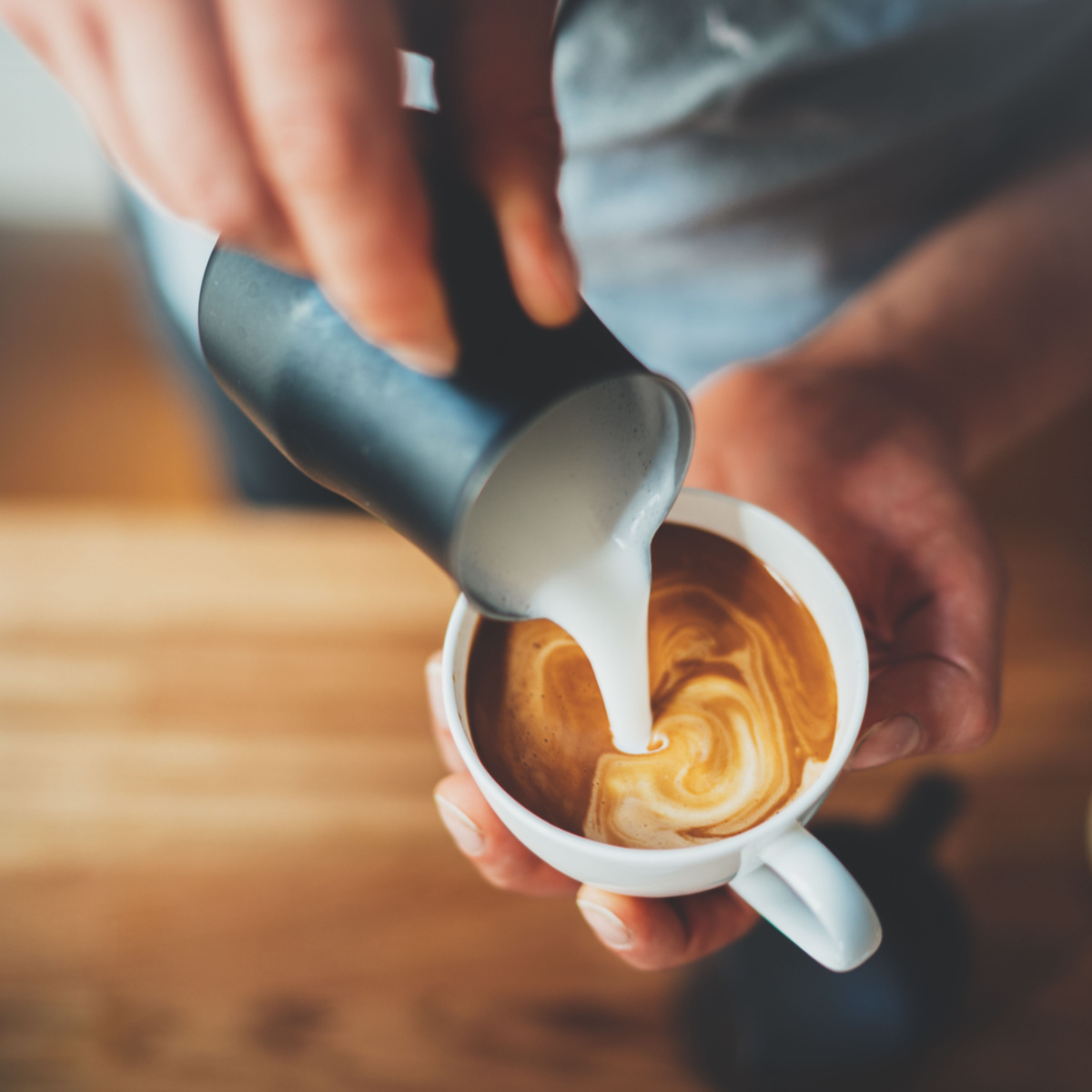 man pouring milk over coffee