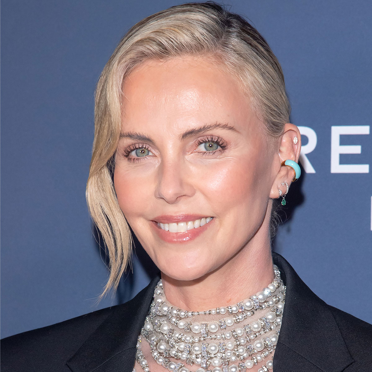 Charlize Theron Displays Her Toned Legs In A Tennis Skirt While Hosting The 20th Annual Desert Smash As Fans React: ‘She Looks 25’