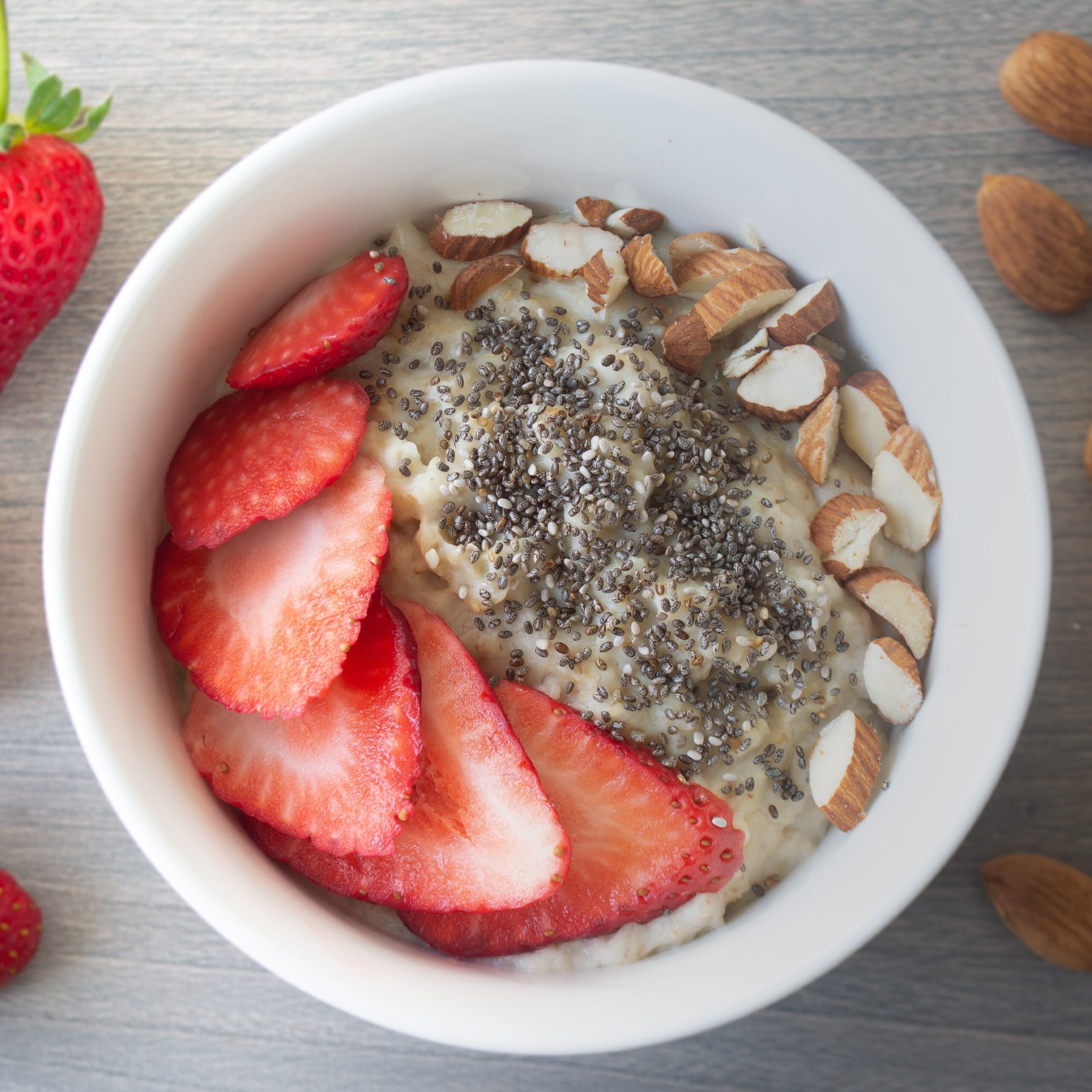 bowl of oatmeal topped with chia seeds almonds and strawberries
